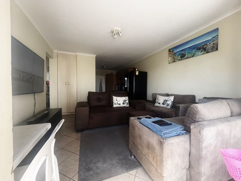 A functional living room featuring tiled flooring, a built-in storage cupboard, and neutral wall finishes, offering a comfortable and practical living space.