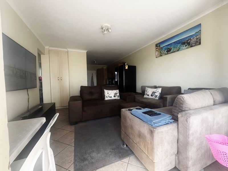 A comfortable living room featuring tiled flooring and a built-in storage cupboard, providing a functional and well-defined space for relaxation.