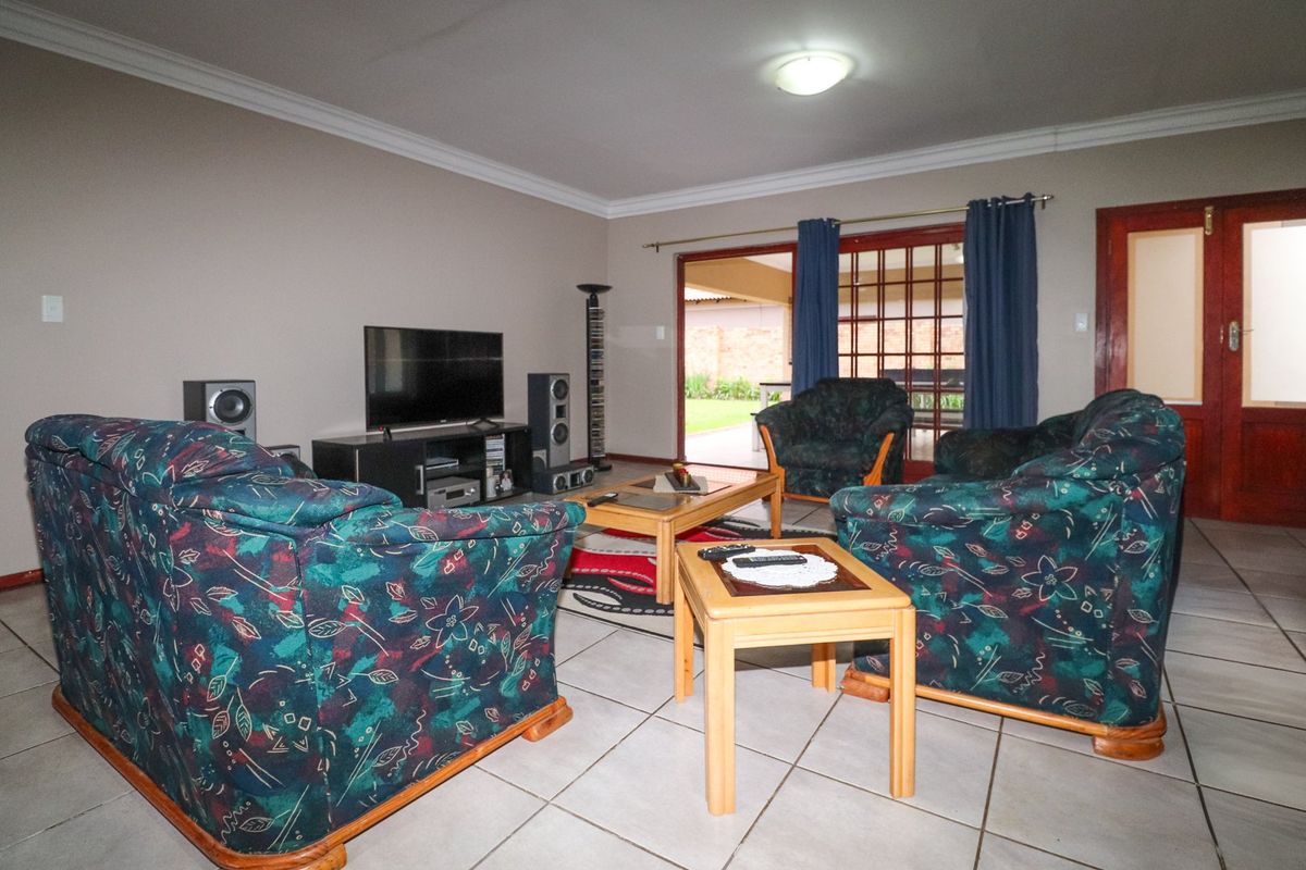 Spacious living room featuring tiled flooring, cove cornicing, and a sliding glass door providing direct access to the outdoor patio area.