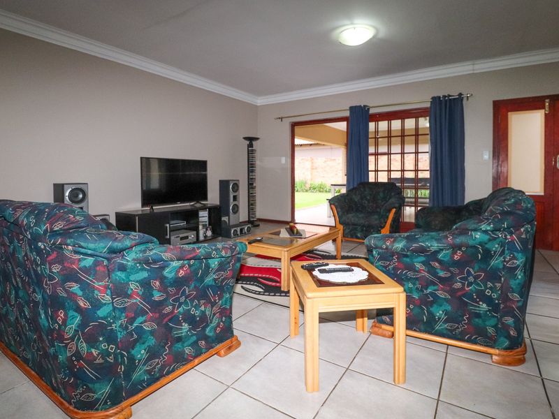 Spacious living room featuring tiled flooring, cove cornicing, and a sliding glass door providing direct access to the outdoor patio area.