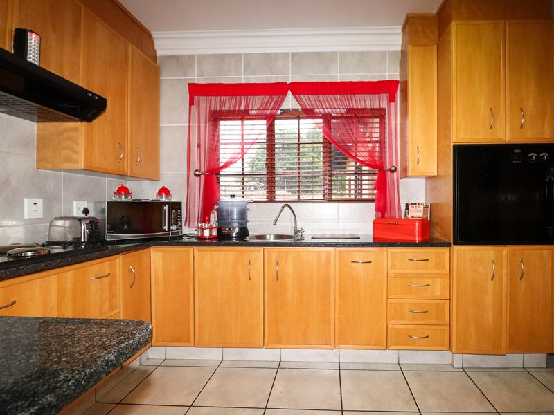 A functional kitchen featuring wooden cabinetry, granite countertops, a built-in oven, and tiled finishes throughout.