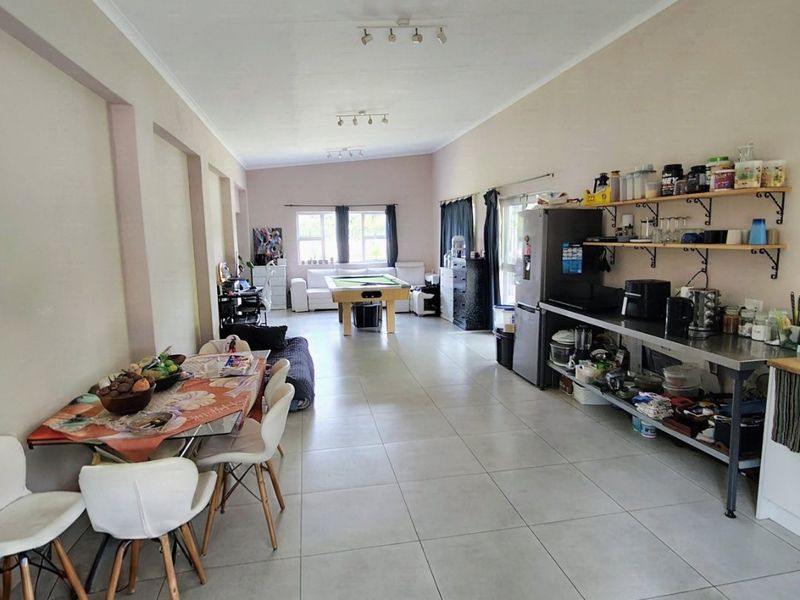 Spacious open-plan living area featuring large format floor tiles, track lighting, and an industrial-style kitchen prep area with open shelving.