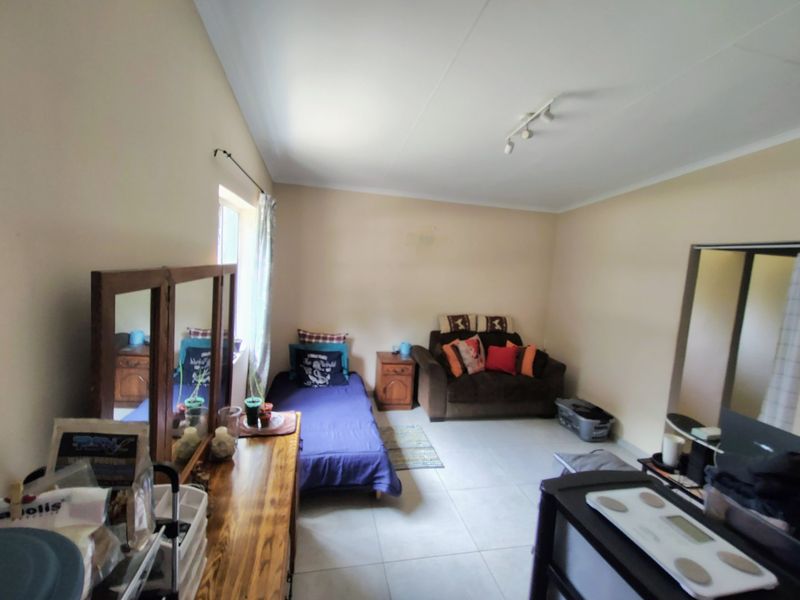 A functional bedroom featuring tiled flooring and track lighting, offering a neutral base ready for personalization or updated interior design.