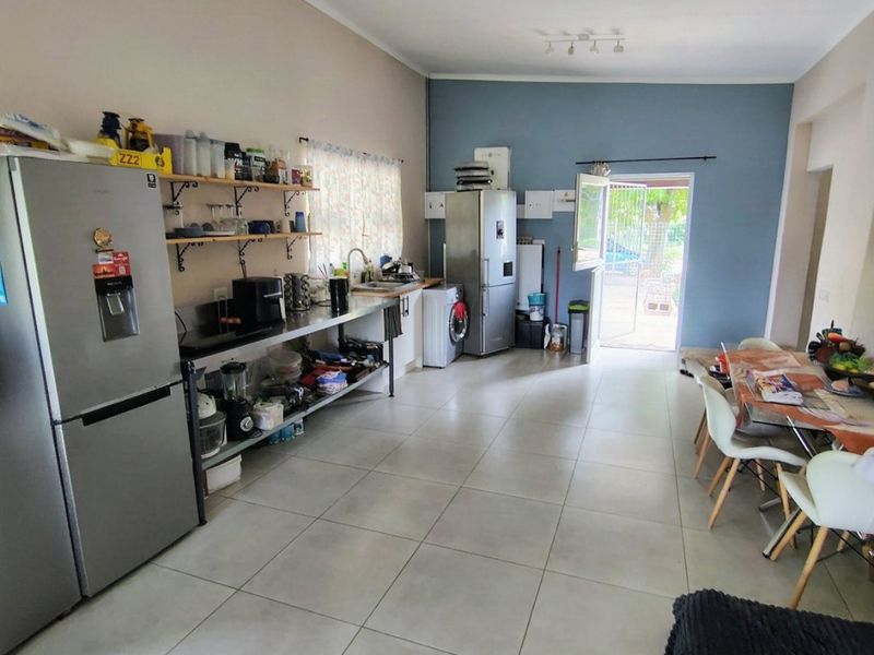 Open plan living and kitchen area featuring tiled flooring, stainless steel prep surfaces, and direct access to the exterior.
