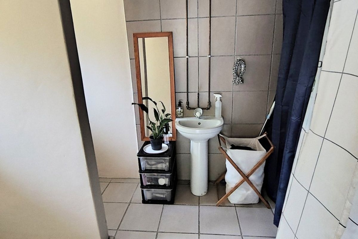 A functional bathroom featuring a pedestal basin, tiled wall and floor finishes, and exposed plumbing fixtures.