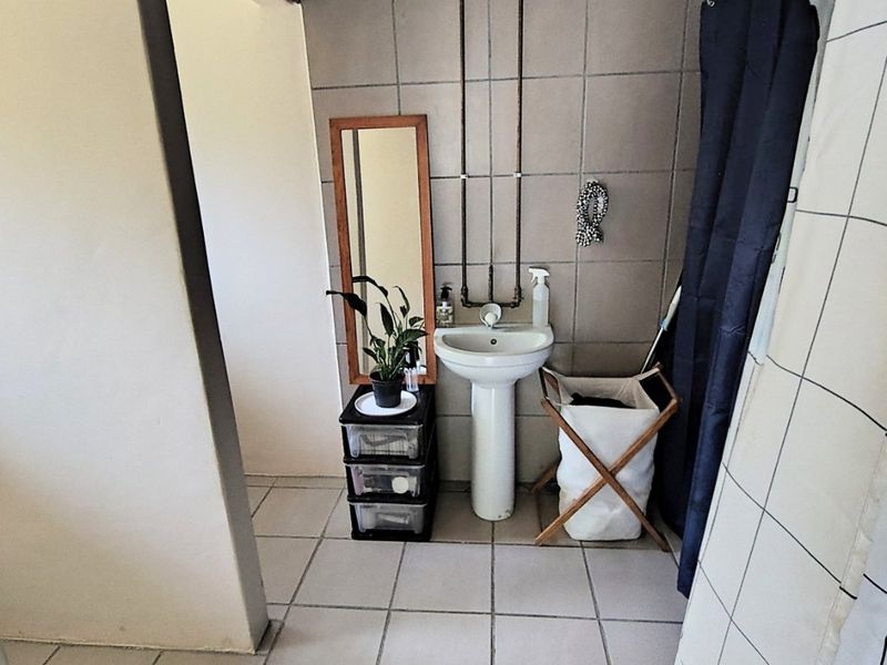 A functional bathroom featuring a pedestal basin, tiled wall and floor finishes, and exposed plumbing fixtures.