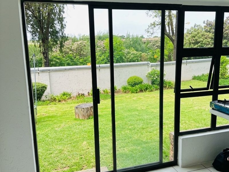 A bright, tiled patio area featuring large sliding glass doors that provide direct access to a private garden space.