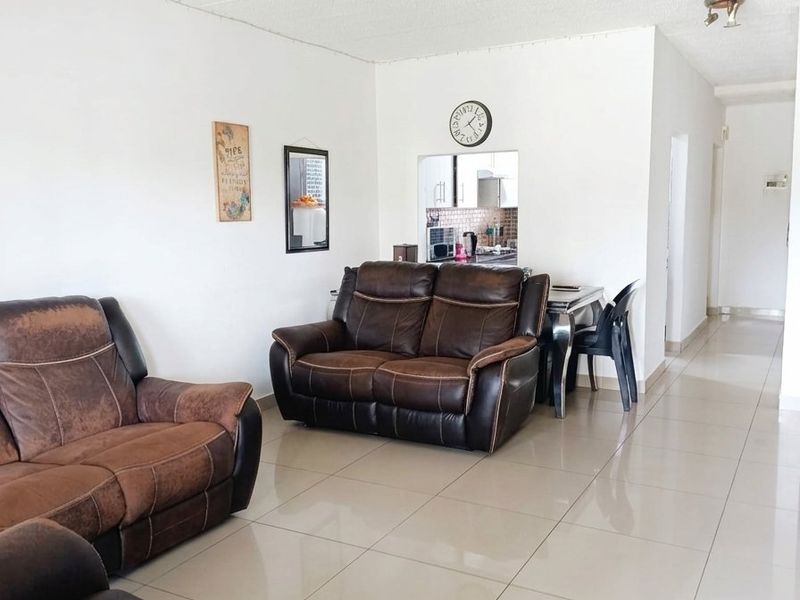 Open plan living area featuring neutral tiled flooring and a convenient pass-through window connecting to the kitchen space.