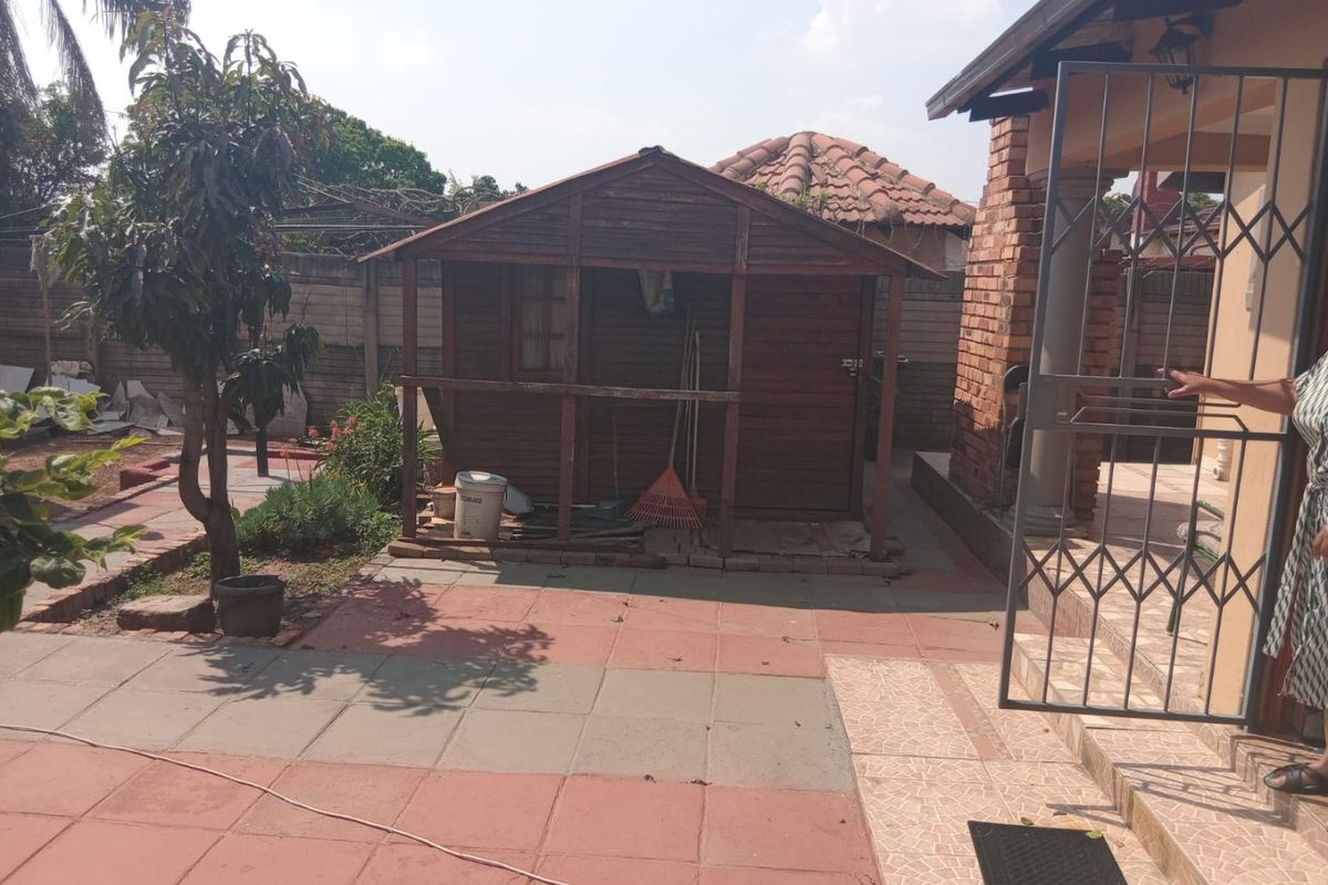 Rear garden area featuring a paved patio, a wooden storage shed, and secure perimeter walling.