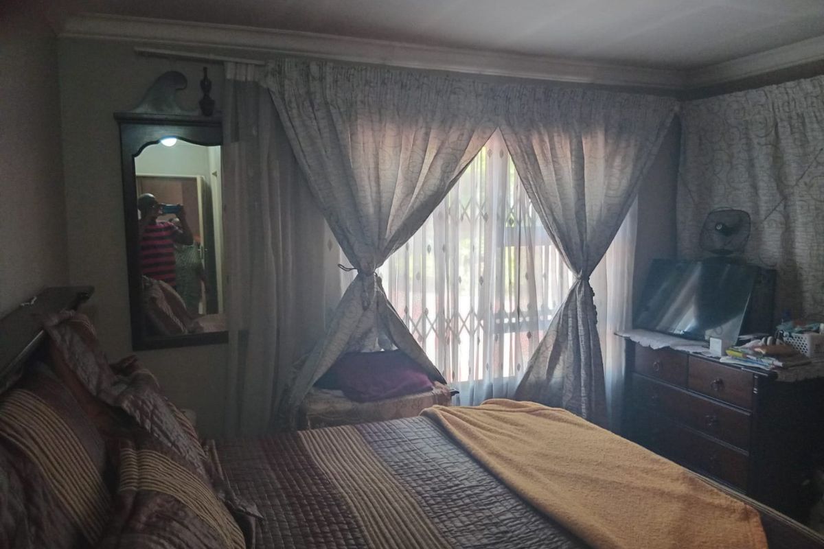 A bedroom featuring crown molding, a security gate on the window, and a wall-mounted mirror.
