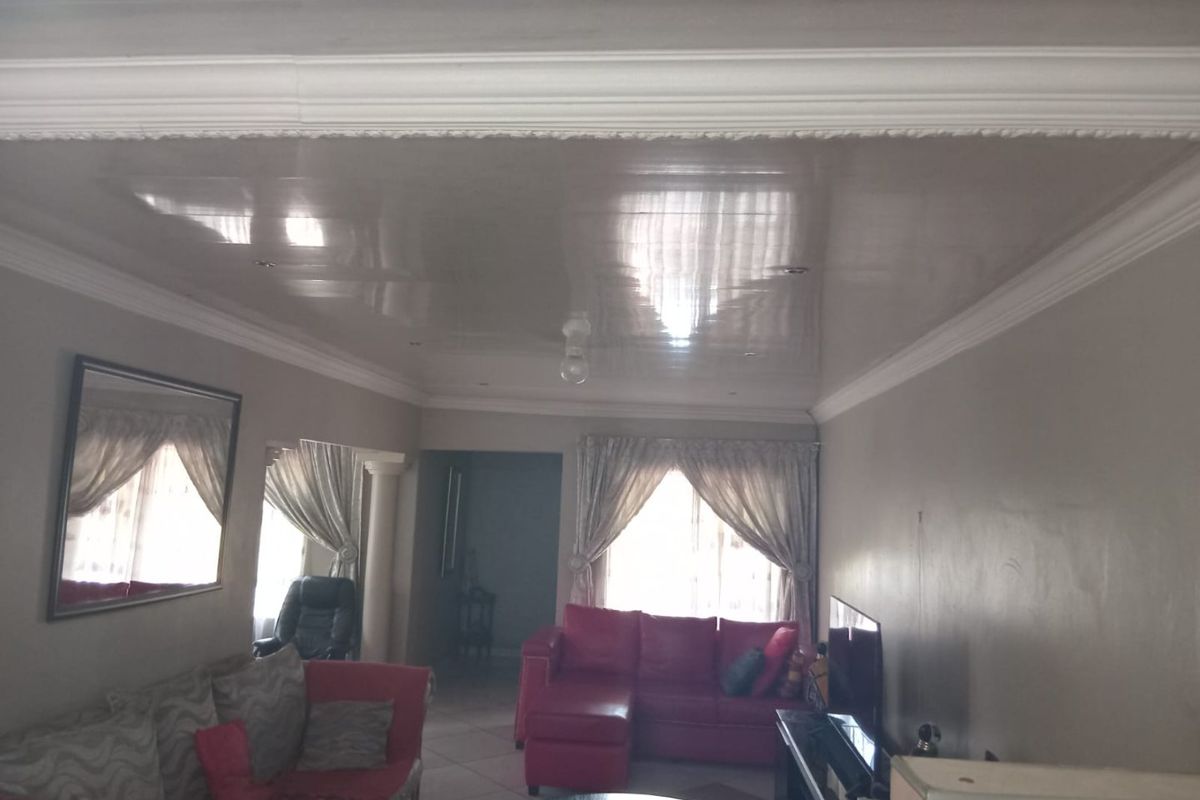 Living room featuring a high-gloss ceiling with decorative crown molding, tiled flooring, and recessed lighting, offering a functional space for relaxation.