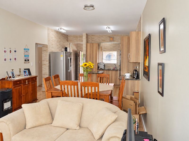 Open-plan living and dining area featuring a functional kitchen with built-in cabinetry, stone countertops, and tiled backsplash, creating a cohesive and practical living space.