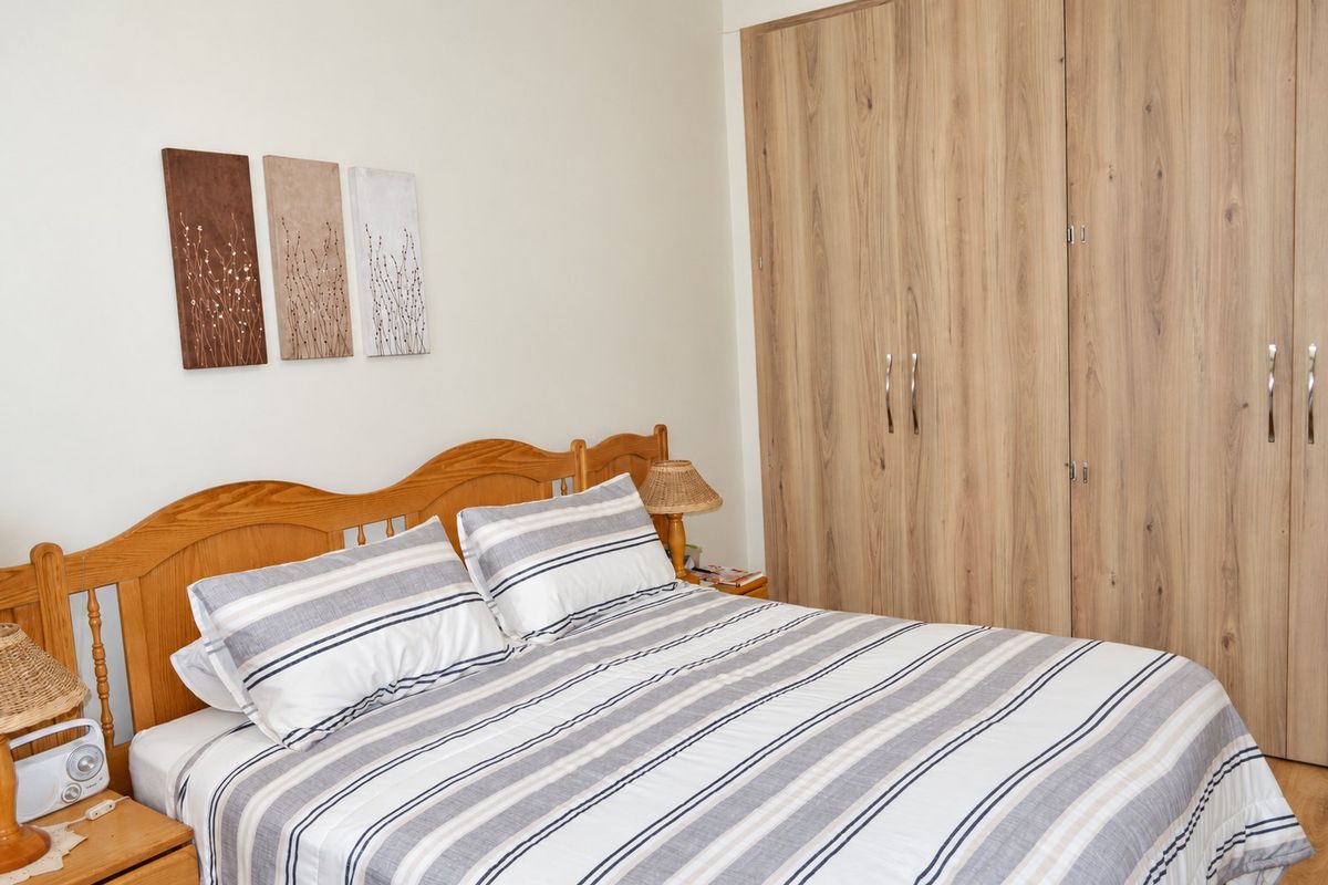 A well-maintained bedroom featuring light wood-tone built-in wardrobes and laminate flooring, offering a clean and functional living space.