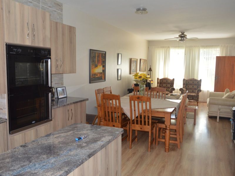 Open-plan living and dining area featuring a modern kitchen with built-in oven, stone-look countertops, and laminate flooring throughout.
