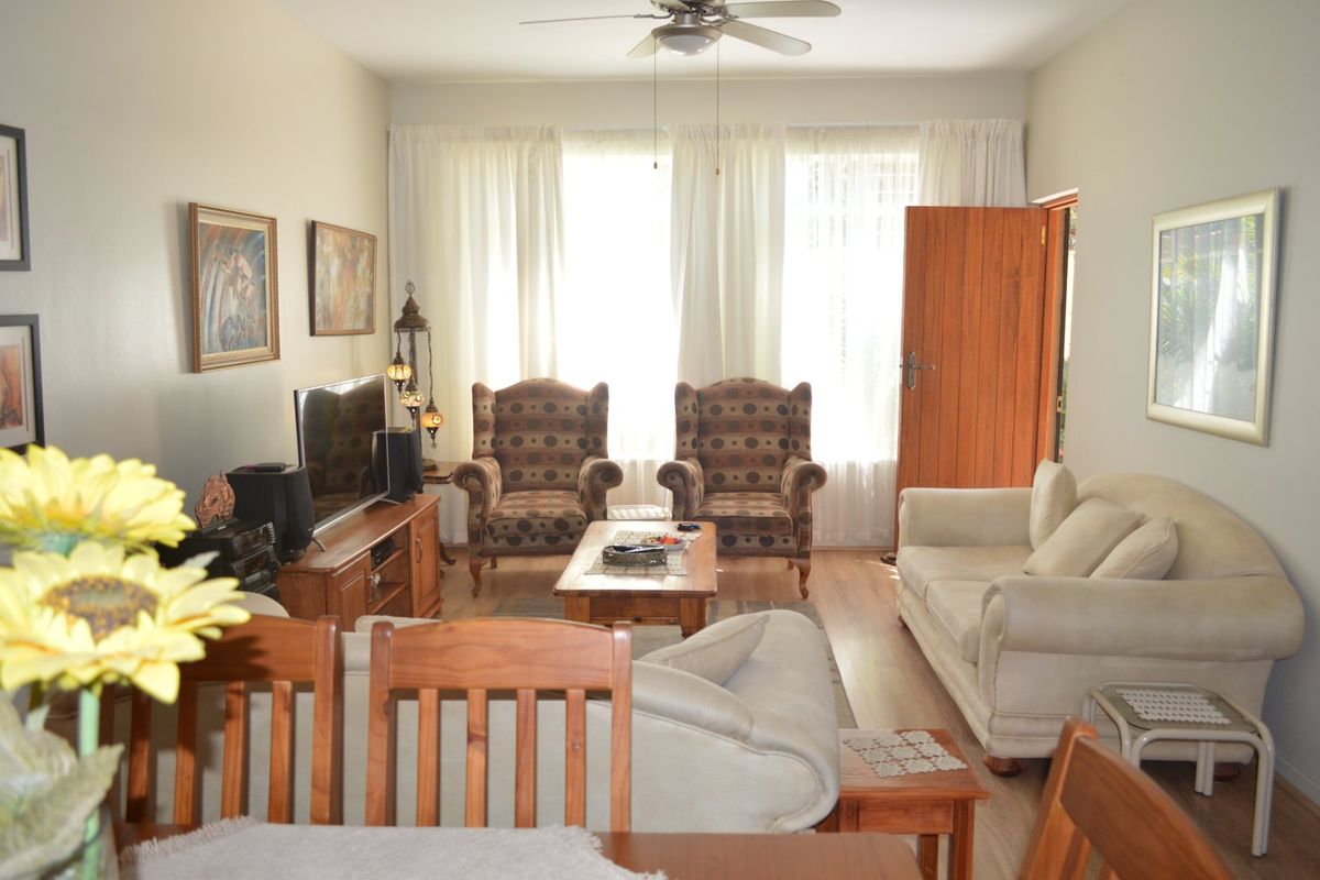 A comfortable living room featuring laminate flooring, a ceiling fan, and direct access to an outdoor area through a wooden door.