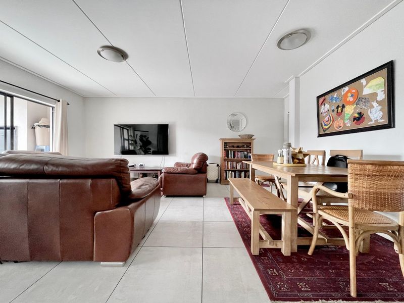 Spacious open-plan living and dining area featuring neutral tiled flooring and direct access to an outdoor patio through a sliding glass door.