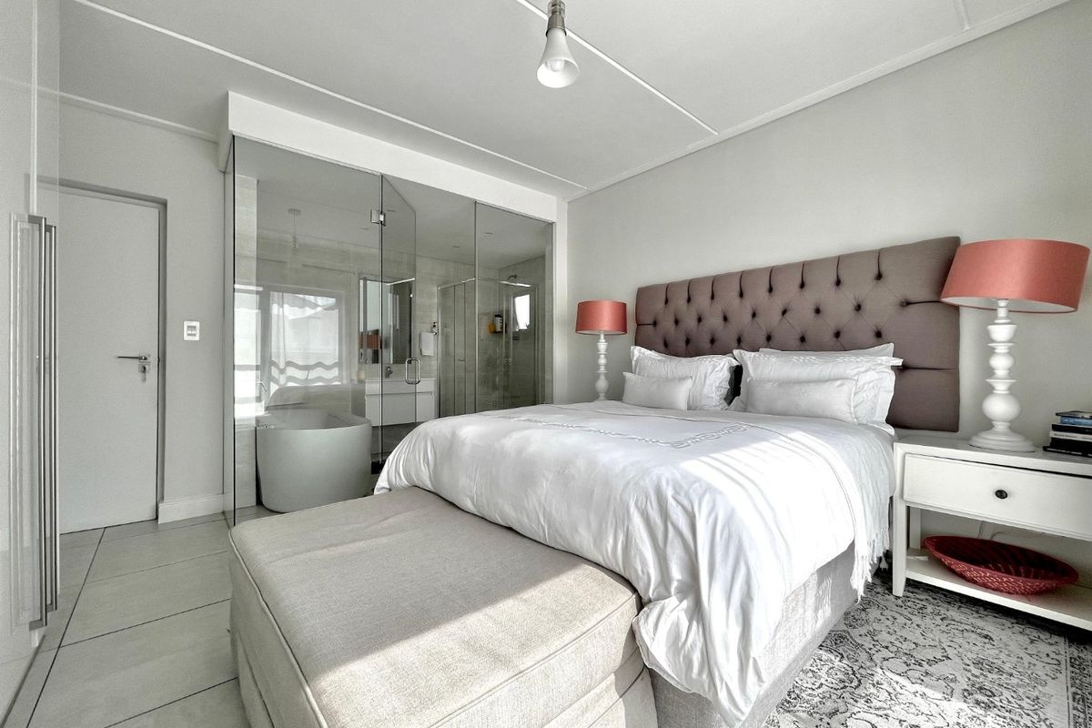 Modern bedroom featuring tiled flooring and a contemporary glass-enclosed en-suite bathroom, creating an open and bright living space.