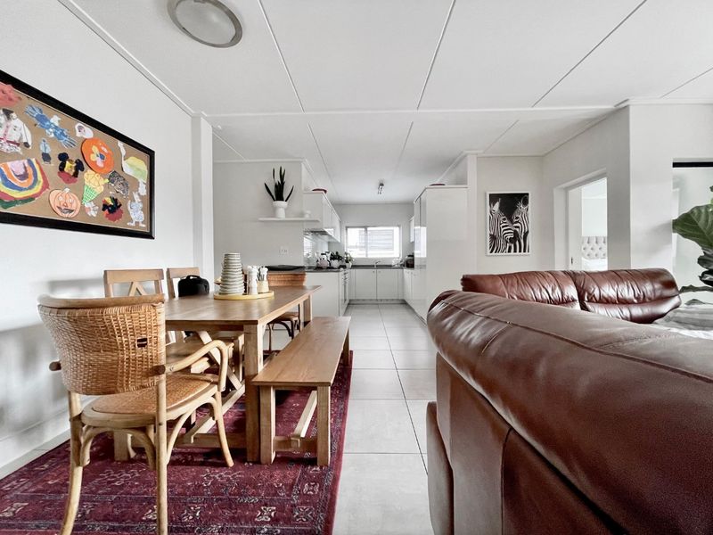 An open-plan living and dining area flowing into a functional kitchen with tiled flooring and neutral cabinetry.