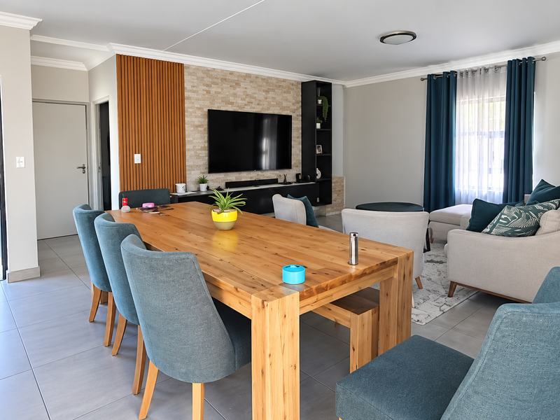 Spacious open-plan living and dining area featuring modern tiled flooring, a stylish stone feature wall with timber accents, and integrated shelving.