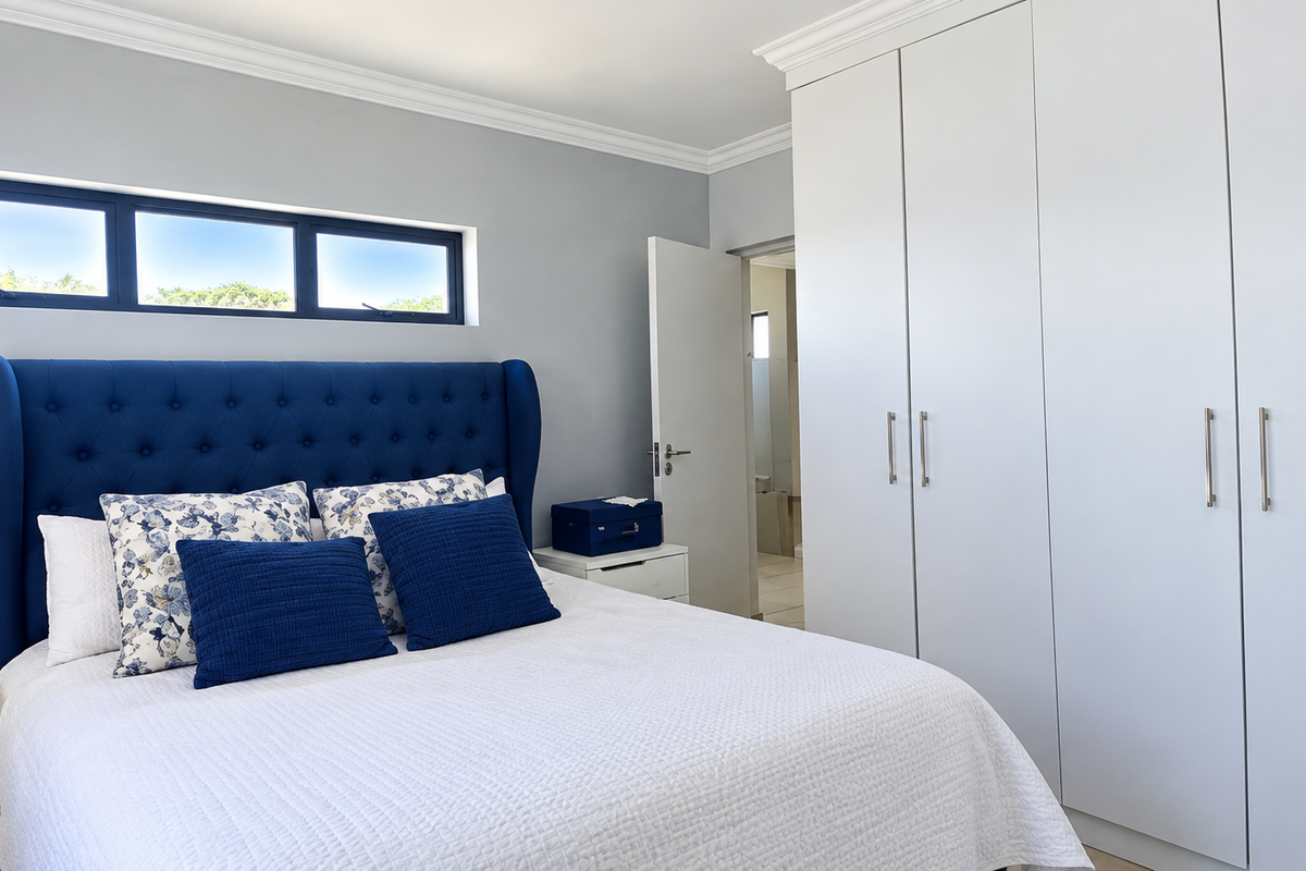 A well-maintained bedroom featuring built-in cupboards, decorative cornice, and a modern horizontal window, offering a clean and bright living space.