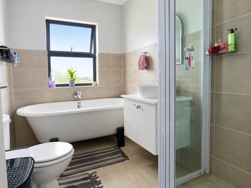 A modern bathroom featuring a freestanding bathtub, a vessel sink vanity, and a separate glass-enclosed shower with neutral wall and floor tiling.