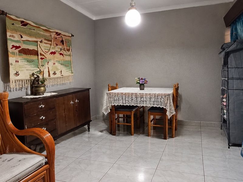 A functional dining area featuring neutral wall finishes, tiled flooring, and classic cove cornicing, providing a versatile space for family meals.