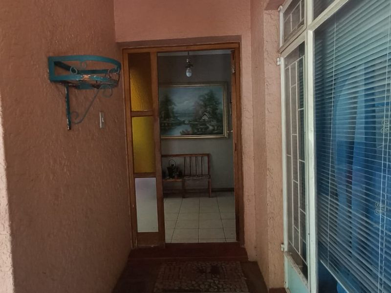 Entrance area featuring a security gate, textured walls, and tiled flooring leading into the home interior.