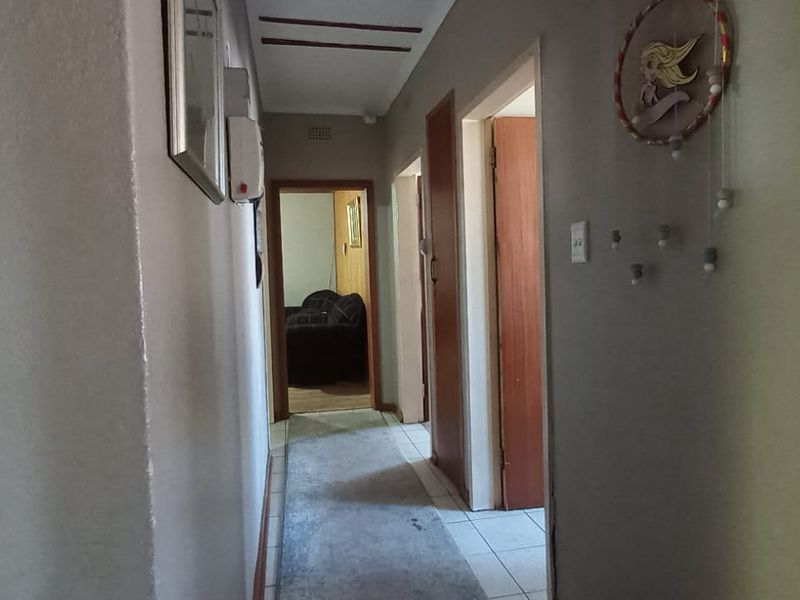 A functional hallway featuring tiled flooring and access to multiple rooms, showing signs of wear on the wall surfaces.