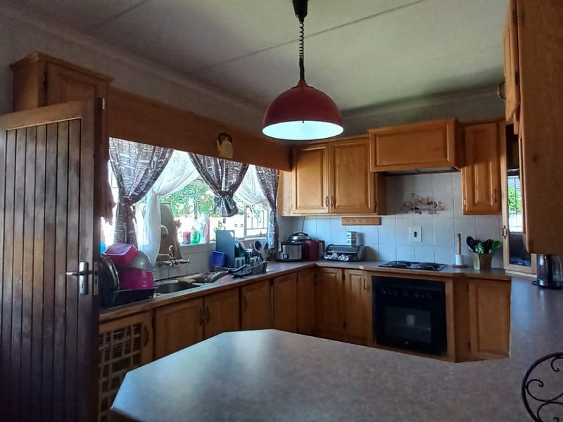 A functional kitchen featuring traditional wooden cabinetry, built-in oven, electric hob, and laminate countertops, offering a classic layout with ample storage space.