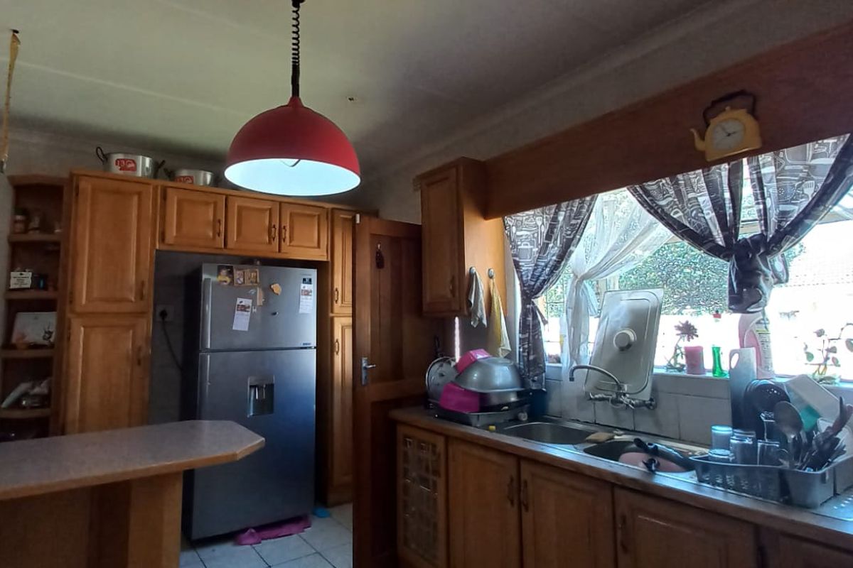 A dated kitchen featuring wooden cabinetry, laminate countertops, and a double basin sink, offering potential for a modern renovation.