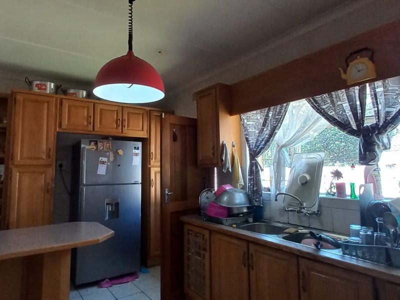 A dated kitchen featuring wooden cabinetry, laminate countertops, and a double basin sink, offering potential for a modern renovation.