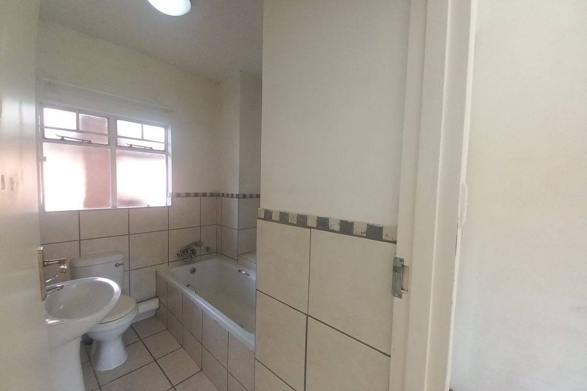 A functional bathroom featuring a pedestal basin, toilet, and bathtub with tiled finishes, offering a clean space ready for modern updates.