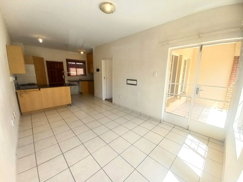 Open-plan living and kitchen area featuring tiled flooring, built-in cabinetry, and direct access to an outdoor patio through a glass door.