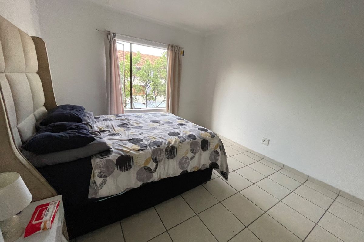 A simple bedroom featuring tiled flooring and a window with natural light.