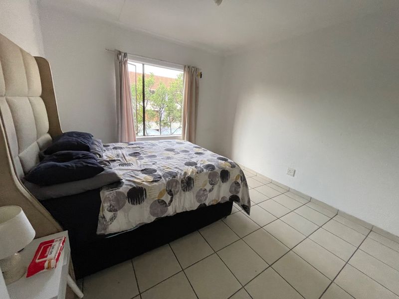 A simple bedroom featuring tiled flooring and a window with natural light.