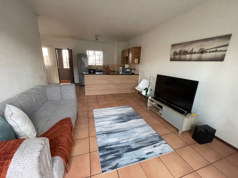 Open plan living area featuring tiled flooring and a functional kitchen with built-in cabinetry and a breakfast counter.