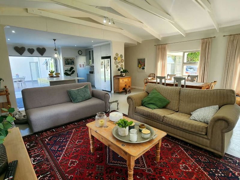 Spacious open-plan living and dining area featuring exposed timber beams, tiled flooring, and a modern kitchen with a central island.