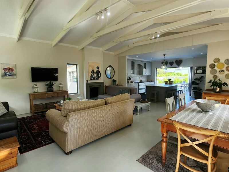 Spacious open-plan living and dining area featuring vaulted ceilings with exposed beams, a cozy fireplace, and a modern kitchen with a central island.