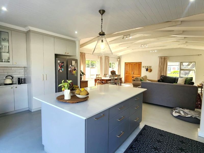 Spacious open-plan living area featuring a modern kitchen with a central island, quartz countertops, shaker cabinetry, and exposed ceiling beams.