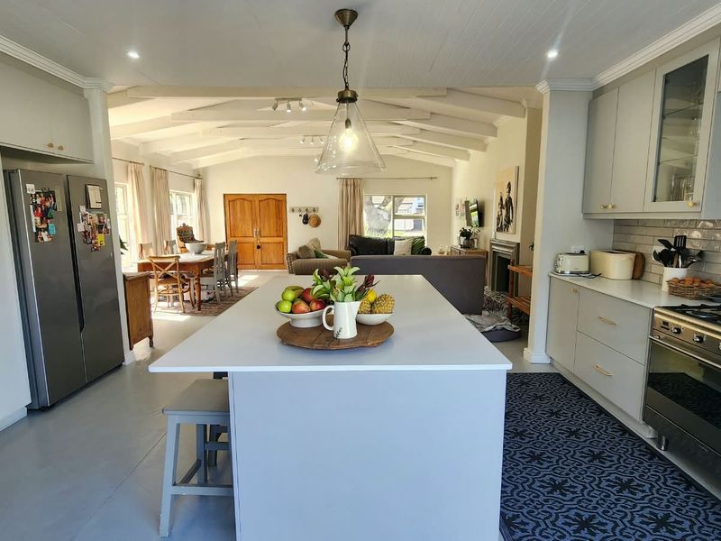 Spacious open-plan kitchen and living area featuring a central island, modern cabinetry, gas stove, and exposed ceiling beams, creating a bright and functional living space.