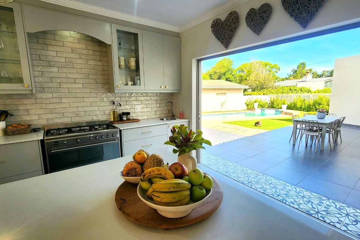 Modern kitchen featuring light grey cabinetry, subway tile backsplash, and a gas stove, with seamless flow to an outdoor patio and pool area.