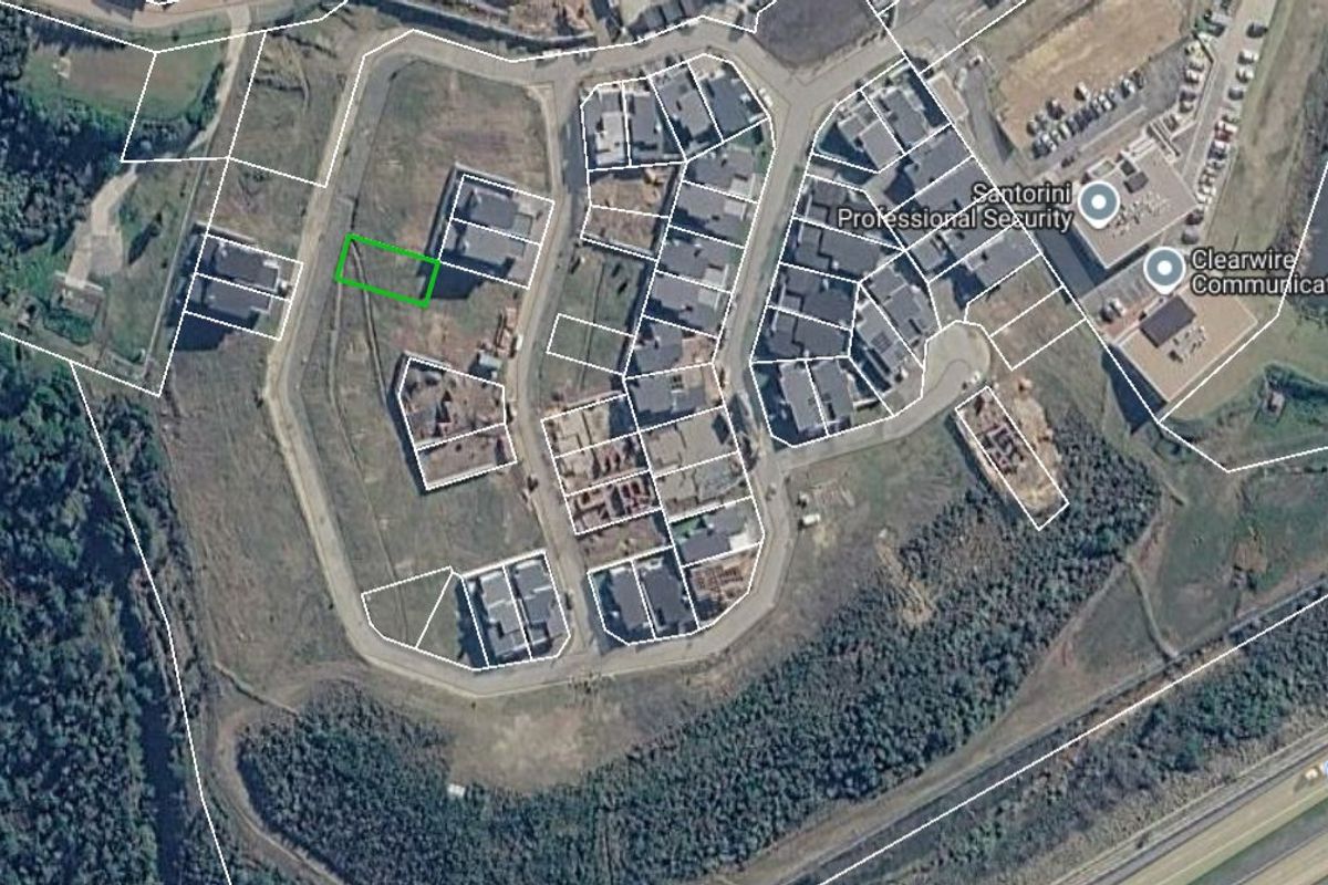 Aerial view of a vacant residential land plot within a developed estate, showing surrounding infrastructure and property boundaries.