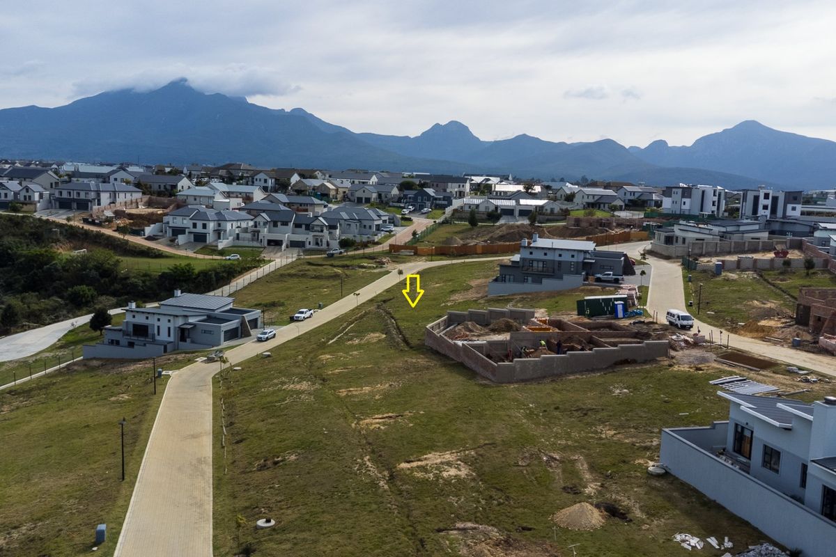 Aerial view of a residential development site with paved roads and surrounding mountain scenery.