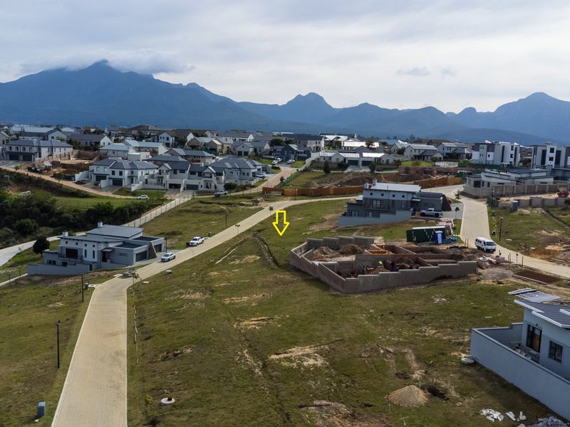 Aerial view of a residential development site with paved roads and surrounding mountain scenery.
