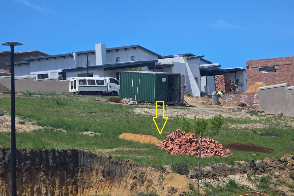 A view of a vacant residential plot under development, featuring uneven terrain, excavation work, and surrounding construction activity.