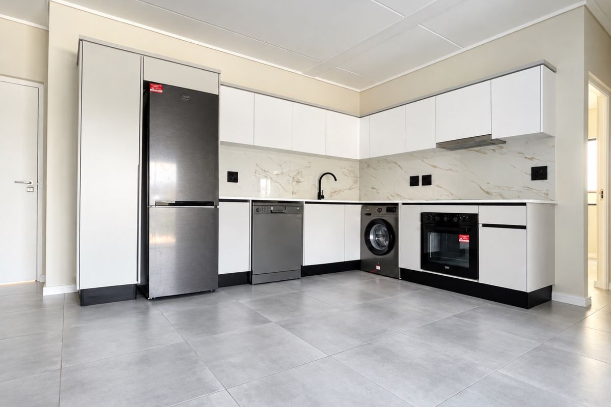 Modern kitchen featuring sleek white cabinetry, marble-look splashback, integrated oven, extractor fan, and neutral tiled flooring in a clean, contemporary layout.