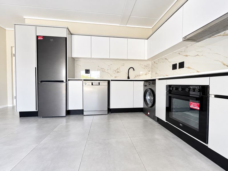 Modern kitchen featuring sleek white cabinetry, marble-look splashback, integrated oven, extractor fan, and high-quality tiled flooring in a clean, contemporary layout.