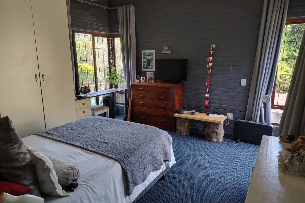 A bedroom featuring an exposed dark brick feature wall, built-in wardrobe, and large windows providing natural light.