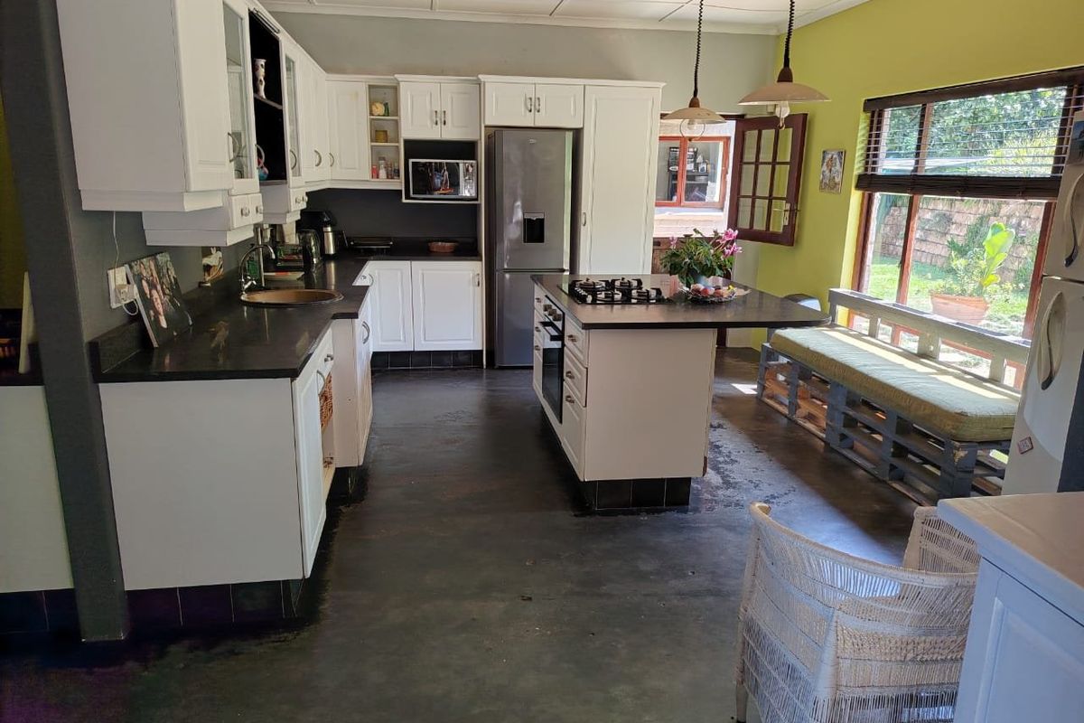 Spacious kitchen featuring white cabinetry, a central island with a gas hob, and direct access to the garden area.