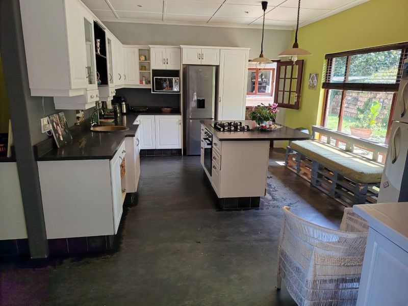 Spacious kitchen featuring white cabinetry, a central island with a gas hob, and direct access to the garden area.